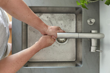 Mann wäscht sich am Waschbecken die Hände mit Seife