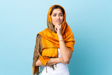 Young Moroccan woman with traditional costume isolated on blue background having doubts and thinking