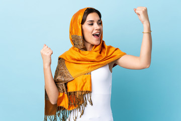 Young Moroccan woman with traditional costume isolated on blue background celebrating a victory