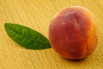 A large, ripe peach lies on a wooden board