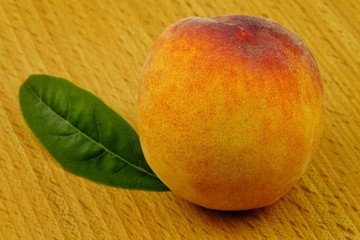A large, ripe peach lies on a wooden board