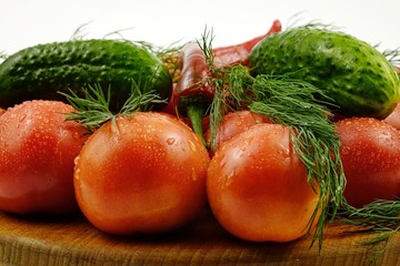 Green dill, cucumbers, chili peppers and tomatoes lie on a wooden board