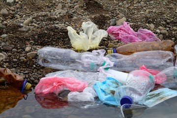 Accumulation of plastic waste in the shallow water of the river, environmental pollution