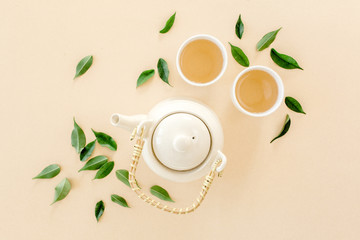 Herbal tea with two white tea cups and teapot, with green tea leaves. Flat lay, top view. Tea...
