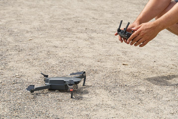 Man using remote control to operating drone assign blurred land.