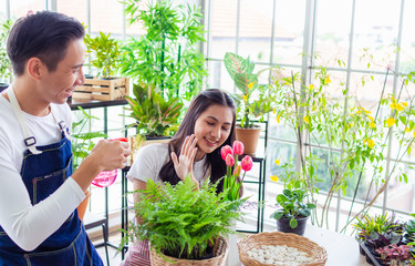 Obraz premium asia handsome man and beautiful woman taking care of her potted plants at home