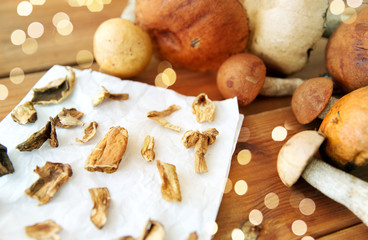 culinary, food and cooking concept - dried mushrooms on baking paper on wooden background