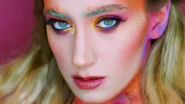 Bright makeup and face art, close-up portrait. Creative makeup, a radiant image with scarlet and yellow tones on the face and neck.