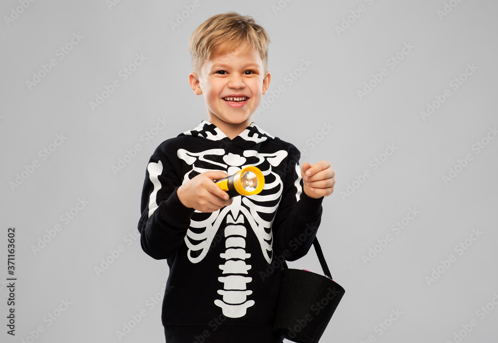 Wall mural halloween, holiday and childhood concept - happy boy in black costume of skeleton with bucket of can