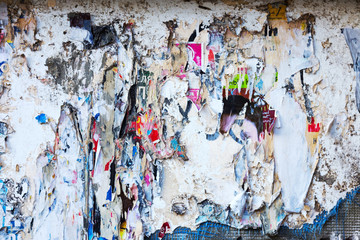 Creative abstract background. Old rough surface of a dilapidated building with traces of old cracked paint and remnants of paper advertising.