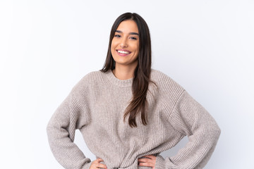 Young brunette woman over isolated white background posing with arms at hip and smiling