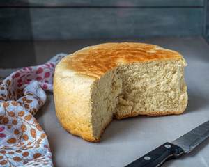 Homemade freshly baked bread in a cut and cotton towel with a pattern on a wooden table