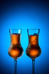 Strong alcoholic drinks in dammed glasses with ice on a blue background.