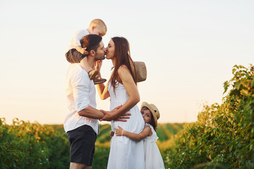 Family of four people spending free time on the field at sunny day time of summer
