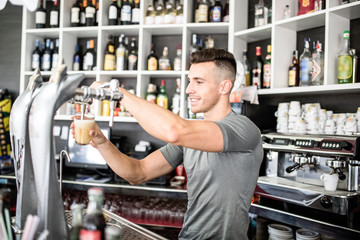 Young bar-man serving beer glass