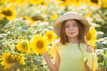 beautiful young teenage girl in hat in a field of sunflowers in summer