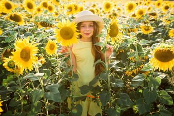 beautiful young teenage girl in hat in a field of sunflowers in summer