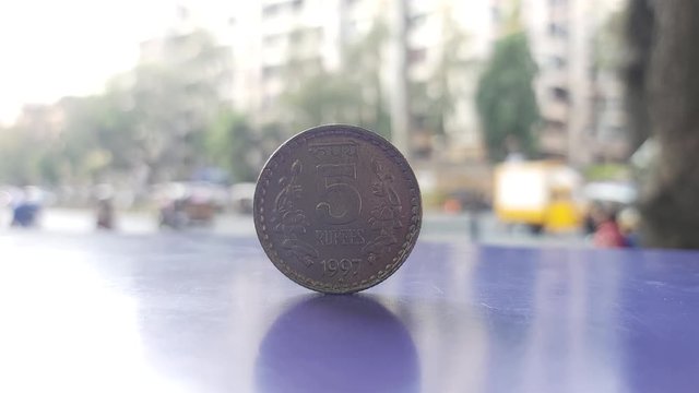 Five rupees Indian currency coin on table with busy street road background in 4K quality 