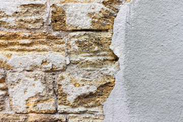 Textured background of an old brick wall, plaster fell off, the building wall was destroyed outside