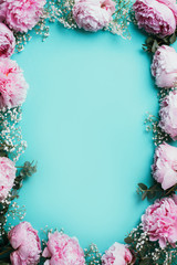 Creative frame pattern of pink peonies, gypsophila flowers, eucalyptus on blue background. Flat lay, top view. Floral composition. Wedding, birthday, anniversary bouquet. Woman day, Mother's day.