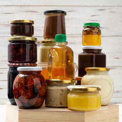 Various canned foods in jars on a light wooden background. Organic food.