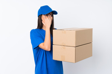 Young delivery woman over isolated white background covering eyes and looking through fingers