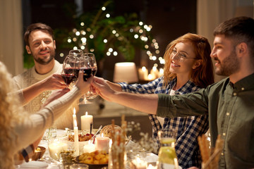 holidays, celebration and people concept - happy friends having christmas dinner party drinking non-alcoholic red wine at home