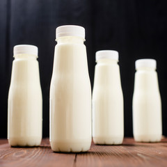 Bottles with milk, yogurt on a wooden background. Natural dairy products.