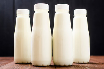 Bottles with milk, yogurt on a wooden background. Natural dairy products.