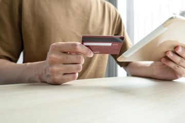 The businessman's hand is holding a credit card and using a smartphone for online shopping and internet payment in the office