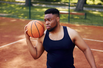 African american man standing with ball on the court outdoors