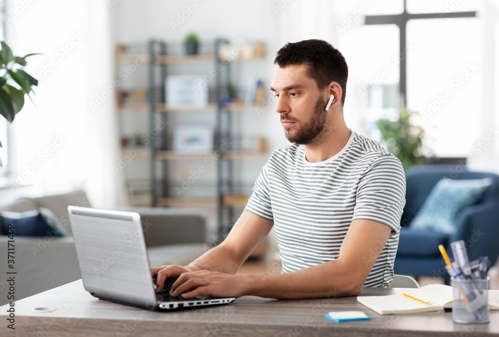 Sticker technology, remote job and business concept - man with laptop computer and earphones working at home