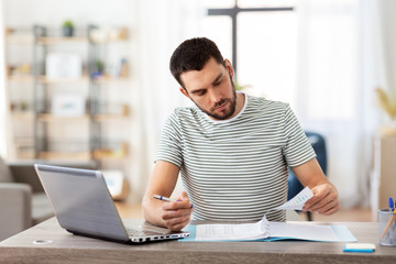 remote job and business concept - man with papers and laptop computer working at home office