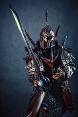 Powerful knight in the armor with the sword. Dark background.