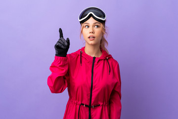 Skier teenager girl with snowboarding glasses over isolated purple background intending to realizes the solution while lifting a finger up