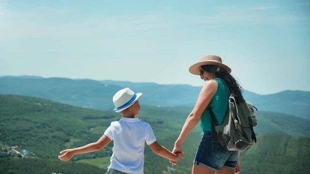 Joyful tourist mother and son clapping hands standing on top of high mountain. 4k Dragon RED camera