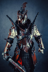 Powerful knight in the armor with the sword. Dark background.