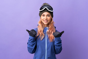 Skier teenager girl with snowboarding glasses over isolated purple background with thumbs up gesture and smiling