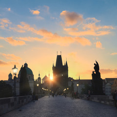 Charles Bridge at dawn. Panoramic image, silhouette of Bridge Tower and city skyline and street lights. Travel in Prague, Czech Republic.
