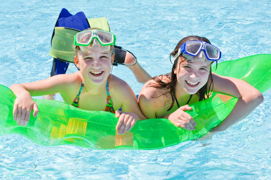 Zwei M&auml;dchen im Wasser mit Luftmatraze und Taucherbrille