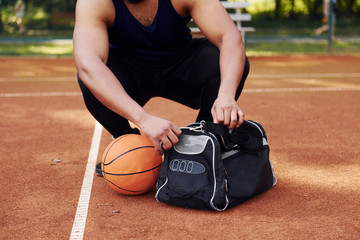 Sits with black bag and preparing for the game. African american man plays basketball on the court...