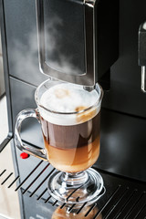hot cappuccino in a glass Cup prepared in a coffee machine