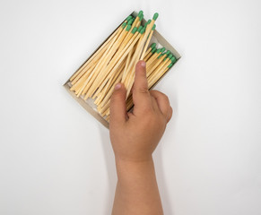 Close-up view of a child playing with matches on a white background. Fire hazard at home concept. The child is in danger. The child plays with matches. Fire hazard concept.
