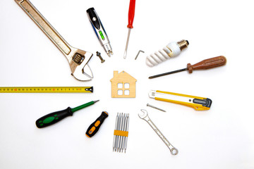 decorating and house renovation tools and other essentials with wooden house on white background top view. flat lay composition