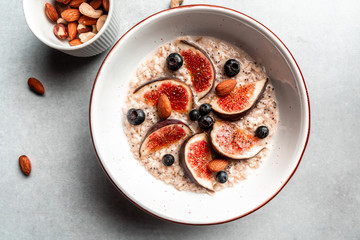 Oatmeal with figs, blueberries, nuts, chia seeds on the gray Background. Healthy Breakfast. Sweet food Dessert. Top View. Flat Lay