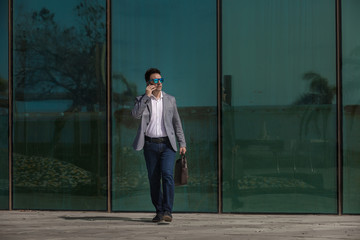 Businessman with smartphone walking on street