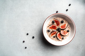 Oatmeal in a bowl with fresh figs, almonds and blueberries. Delicious breakfast or snack on a light background, top view Food for weight loss.