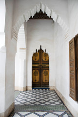 Hallway in a palace, Marrakech, Morocco. Moorish architecture. Romantic interior. Arched doorway and ornaments. Traditional islamic design. Mosaic floor, white walls and wooden decorated doors. 
