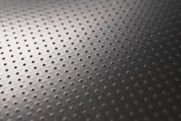 Dark industrial metallic background or wallpaper. Perforated aluminum surface with many holes. Perforation rows go into the distance and form a perspective. Macro