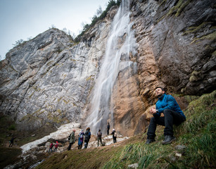 Experienced hiker standing in front of a waterfall with his teammates